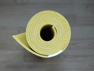 Rolled green yoga mat on a light wooden floor.